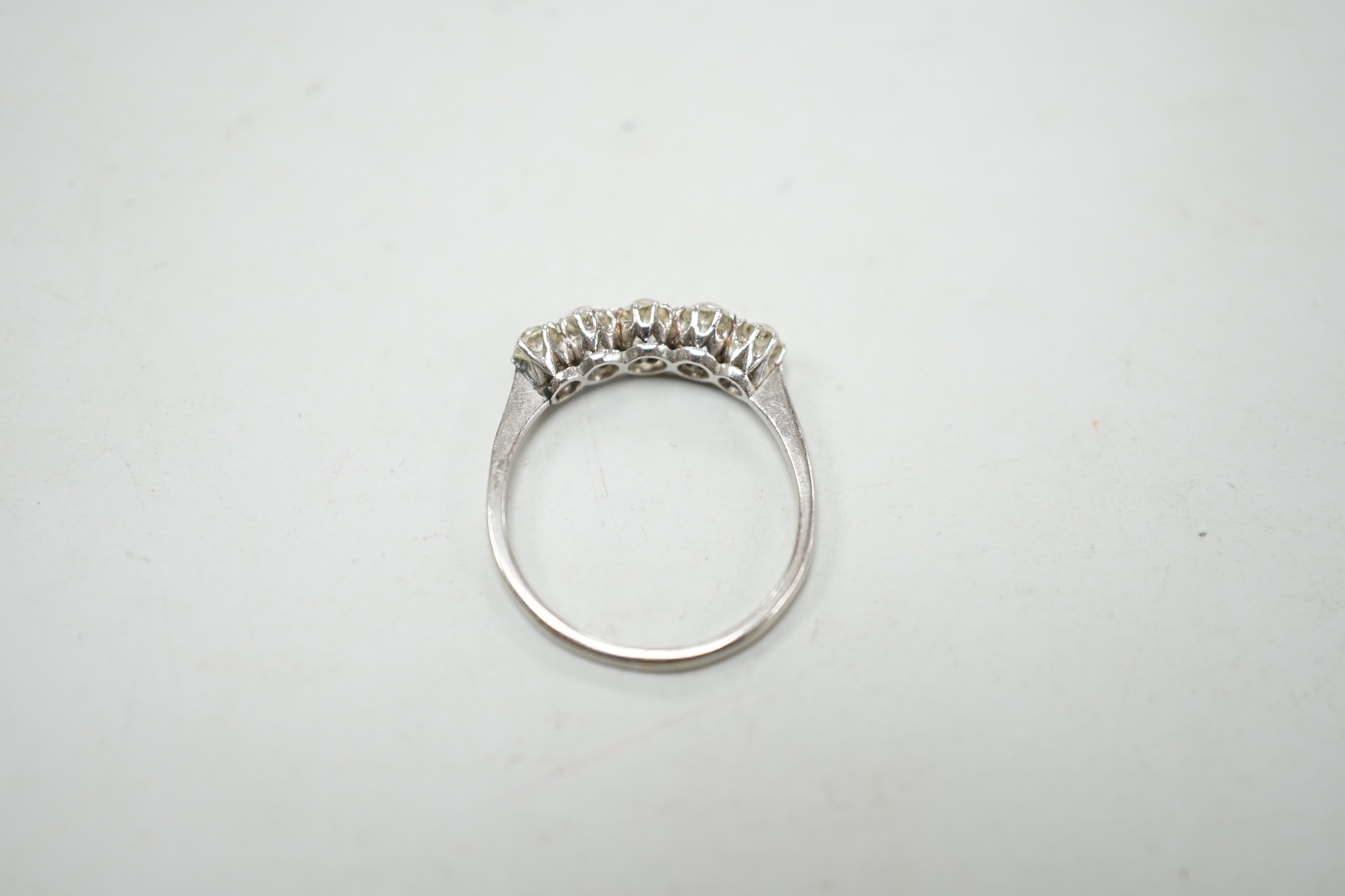 A 1940's white metal and graduated five stone diamond set half hoop ring, size M/N, gross weight 2.8 grams.